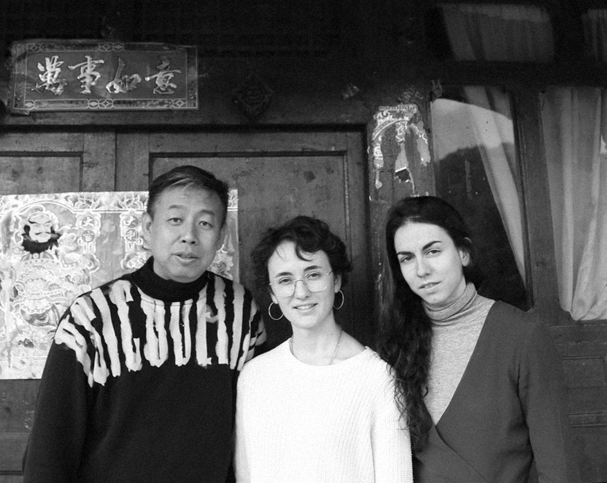 Photographie en noir et blanc représentant trois personnes : le designer chinois Zhang Xing et deux jeunes femmes ; dont l'une est Pauline.